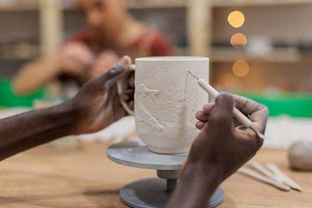 A close-up view of a potter's hand gently touching the surface of a concrete planter to assess the texture following the casting process.