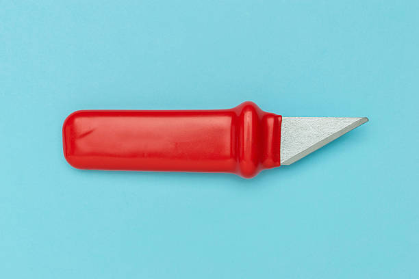 Red Handle Utility Knife on Light Blue Background Reflecting Minimalist Design in Stock Photography