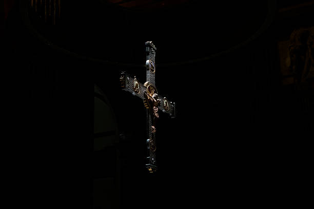 A detailed crucifix hanging inside a dimly lit church with dramatic lighting.