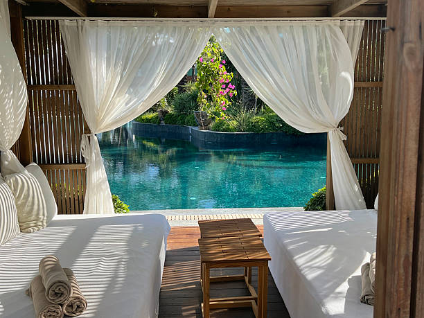 istock Wooden lounger with white curtains and pool view 2233371315
