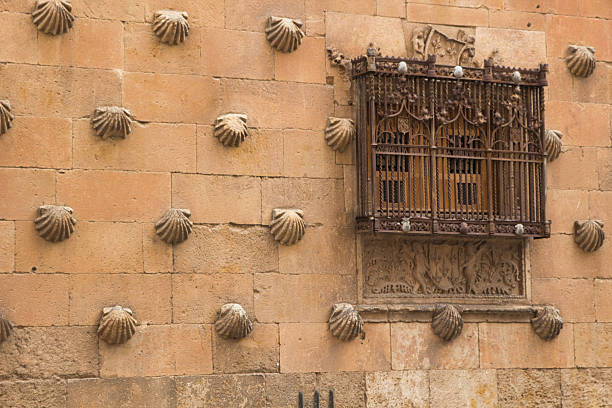 istock Facade with shells at Casa de las Conchas: Historic sandstone wall with scallop shells and ornate window grille in Salamanca's famous Casa de las Conchas, Spain. 2233373381