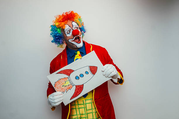 A creepy clown pointing to the blank wall, ready for your text to be be brought attention to.