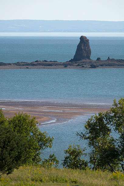 Distant sea stacks formed by erosion stand in the mud flats of Cobequid Bay, an arm of the Bay of Fundy in the Five Island Provincial Park, Nova Scotia, Canada.
