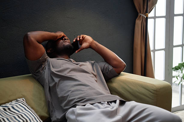 istock Middle Aged Black Man Sitting Indoors Talking on Phone during House Arrest 2233376155