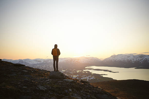 istock Young man stands on hill above lake at midnight 2233379938
