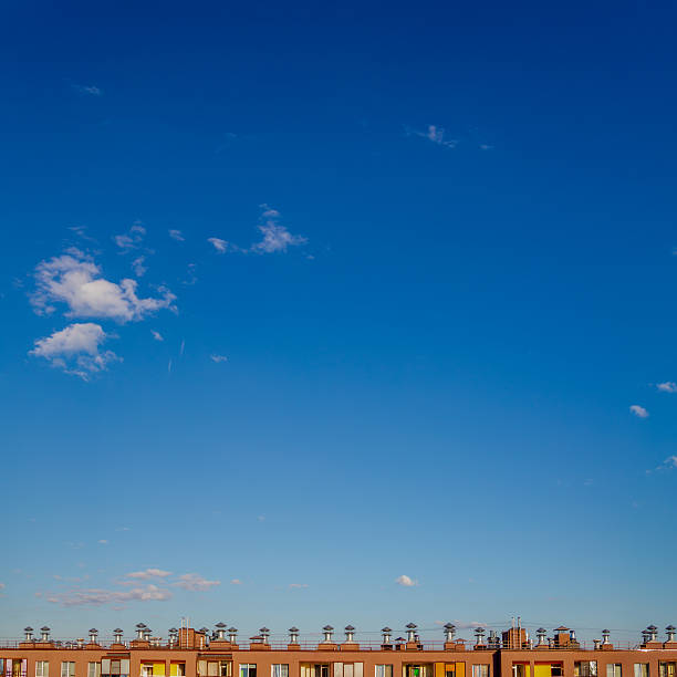 Blue sky with a few clouds and a building in the background. The sky is clear and bright, and the building is tall and brown