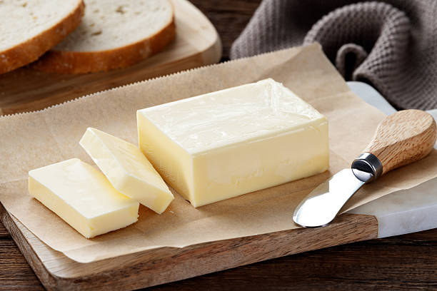 Sliced pieces of butter on a cutting board, wooden background. Piece of butter.