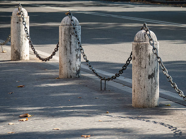 Concrete street bollards with metal chains in Rome, Italy