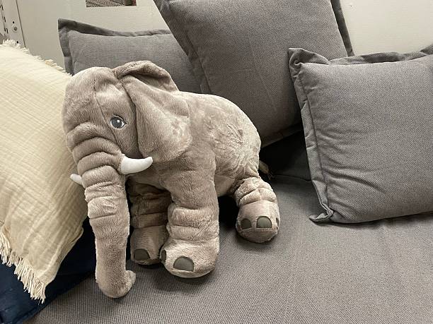 istock Soft Elephant Plush Toy on Grey Sofa with Cushions 2233386158