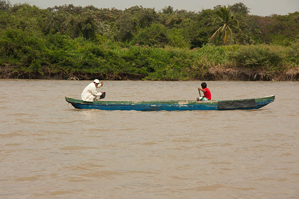 Isla Santay, Guayas, Ecuador - November 25, 2012: Indigenous Ecuadorian people are paddling a traditional canoe on the Guayas River, near Santay Island, demonstrating their connection to nature and ancestral ways of life