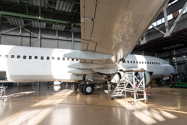 istock White passenger airplane in the aircraft hangar. Checking mechanical systems for flight operations 2233391042