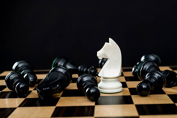 Close up of Chess pieces on a reflective mirror board surface with a plain black background