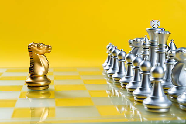 Golden knight and silver chess pieces on chess board.