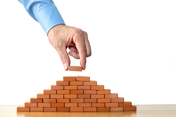 istock Businessman putting toy brick onto a pyramid 2233391959