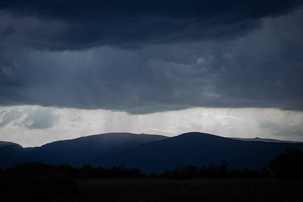 istock Heavy Storm Clouds and Rainfall Curtain Above Distant Mountain Ridges 2233392579