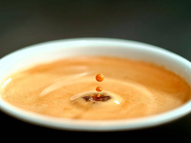 istock close up shot cup of coffee with foam and drop making splash 2233395035