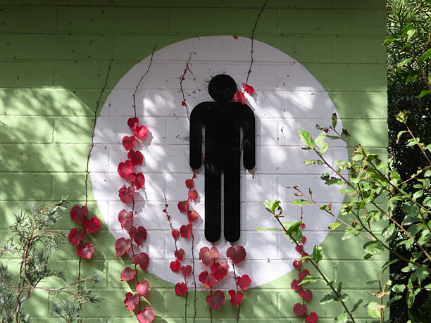 Sign for the men's bathroom with vines growing on the building