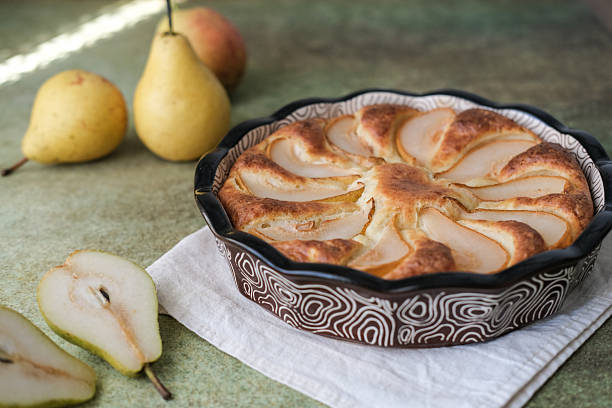 Delicious homemade cottage cheese and pear pie in ceramic baking dish on textured green surface. Warm cozy atmosphere is perfect for food and lifestyle content