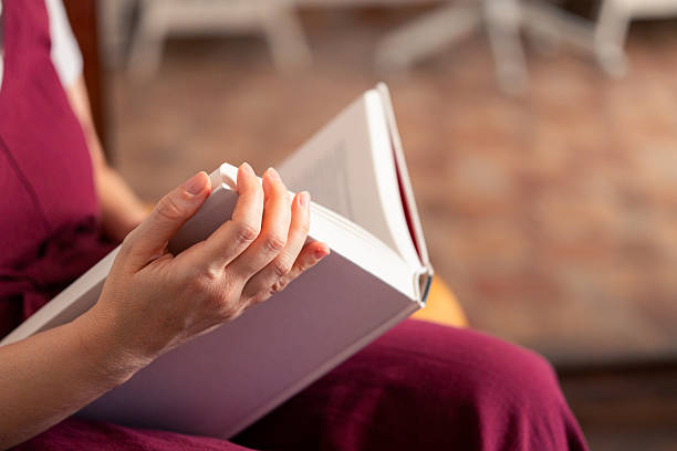 istock Hand holding a book while sitting in a cozy reading nook during daylight hours 2233403976