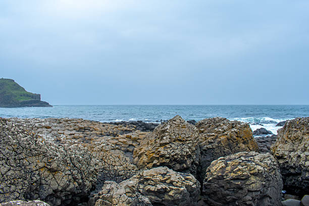 The Giants Causeway is an area of about 40,000 interlocking basalt columns, the result of an ancient volcanic fissure eruption. It is located in County Antrim on the north coast of Northern Ireland, about three miles northeast of the town of Bushmills. The tops of the columns form stepping stones that lead from the cliff foot and disappear under the sea. Most of the columns are hexagonal, although some have four, five, seven or eight sides. The tallest are about 39 ft high.
