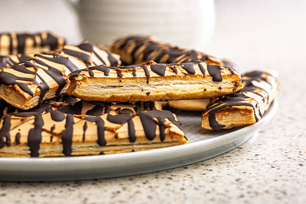 istock Sfogliatine glassate with chocolate. Italian crispy dessert on plate on kitchen table. 2233411052