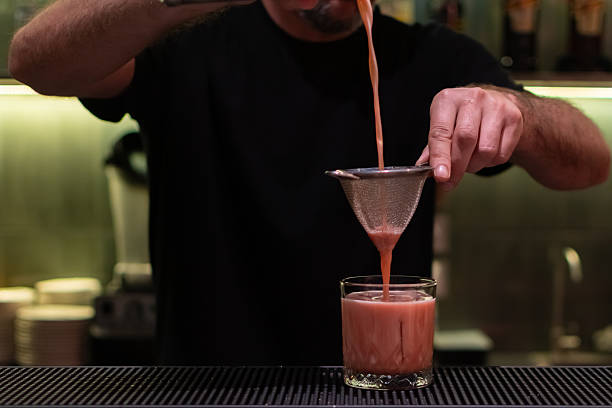 istock Final steps of making a cocktail. Bartender strains the finished drink through a sieve into a glass 2233411442