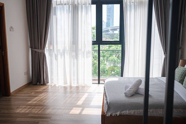 istock Comfortable double bed with fresh linens in a city-view bedroom 2233411768