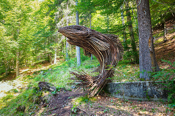 Tarvisio, Italy - August 9, 2025: Wooden sculpture along the Lynx Trail in a lush forest, showcasing artistry and nature's beauty together.