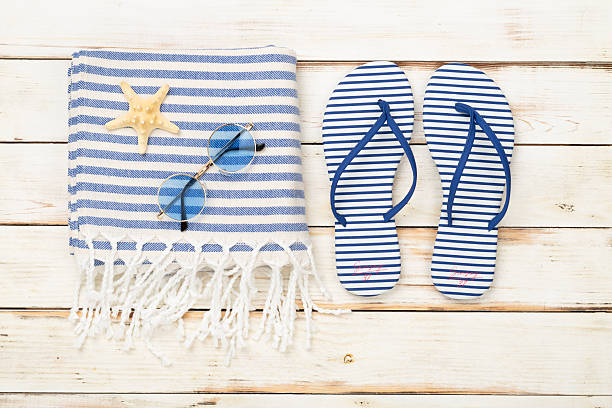 istock Beach towel with summer accessories on wooden background, top view 2233418575