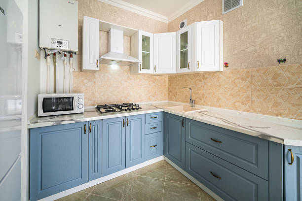 The kitchen is a bright and cheerful space, with blue cabinets and white appliances. The cabinets are a deep blue color, and the appliances are all white. The kitchen has a modern and clean look