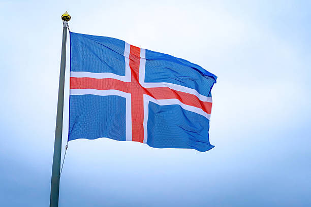 The blue, red, and white national flag of Iceland captured mid-wave against a cloudy sky background