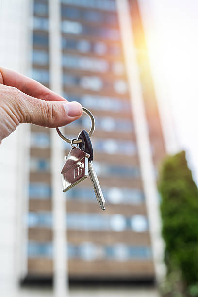 istock Real Estate Deal: Hand Holding Apartment Keys in Front of Modern Building 2233423653