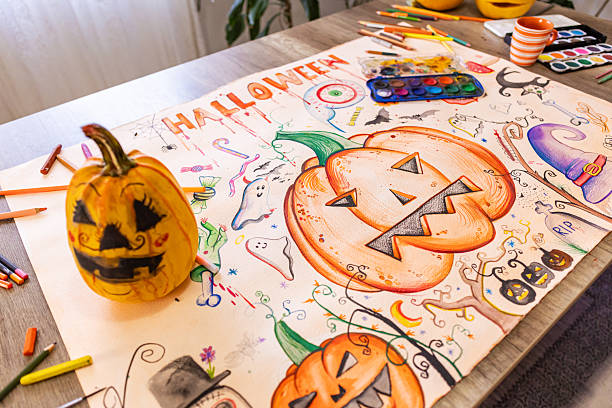 A completed Halloween poster displayed on a table with a real pumpkin and painting supplies.