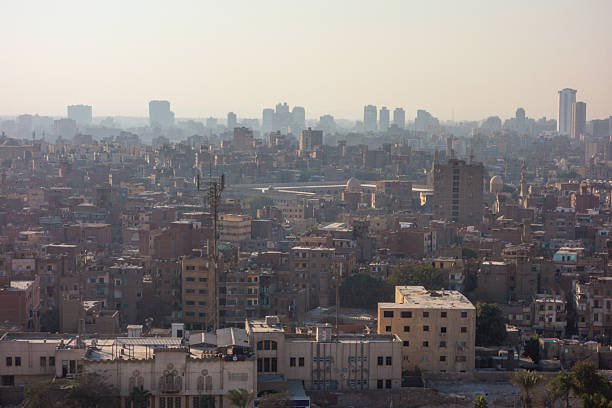 A hazy panoramic view of the vast and sprawling cityscape of Cairo, seen from the elevated vantage point of the Citadel