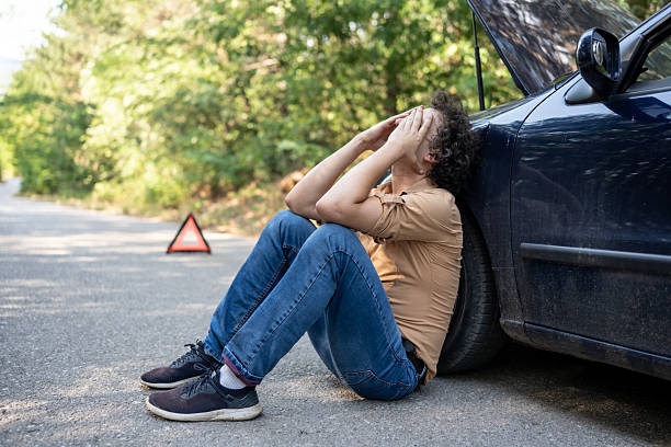 istock Frustrated Man Sitting Beside Car After Breakdown on a Countryside Road 2233430434