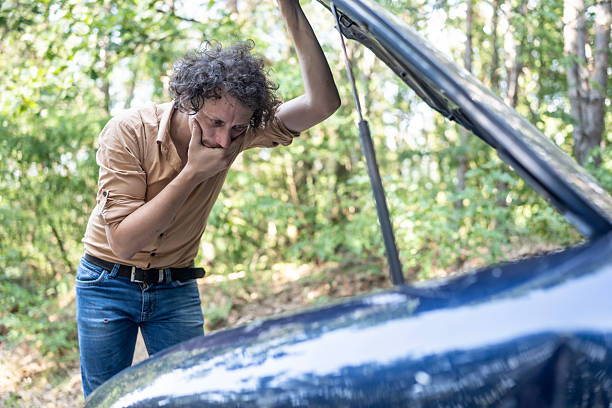 istock Concerned Man Inspecting Car Engine in a Forested Area 2233430445