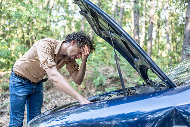 istock Frustrated Young Man Examining Broken Car on a Forested Roadside 2233430452