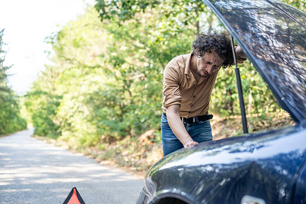 istock Man Checking Under Car Hood on a Remote Forest Road 2233430594
