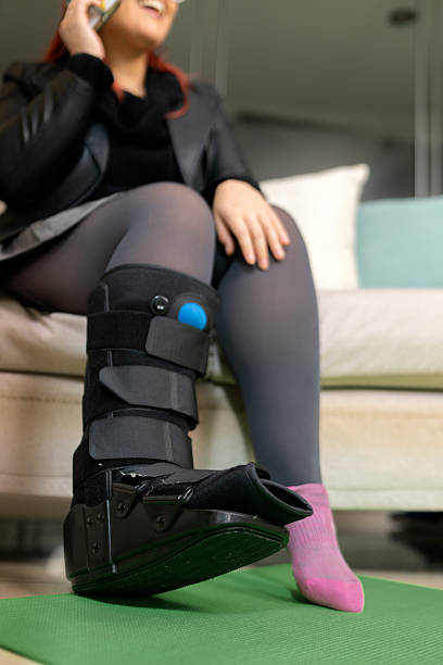istock Woman wearing orthopedic boot talking on phone at home 2233432813