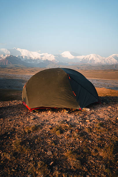 istock Tent on grassy field and mountains at sunset 2233436330