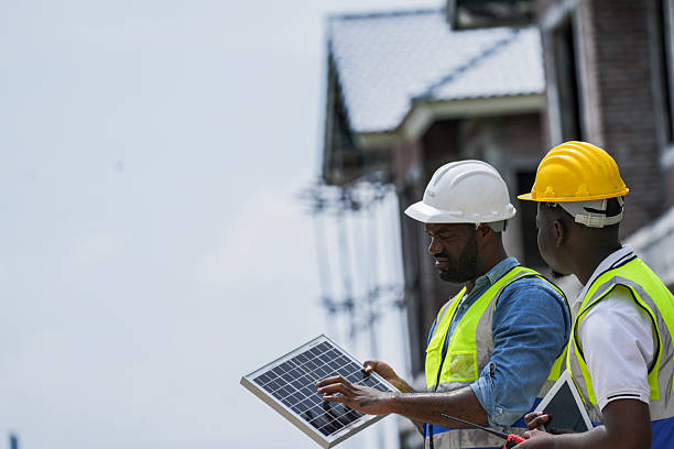 Black professionals collaborating on a renewable energy project. A senior engineer and his partner from a Black owned business discuss a solar installation, representing diversity in tech.