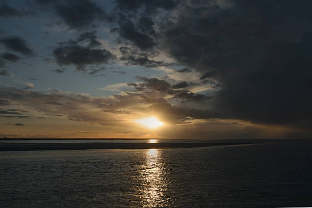 istock Sunset over calm waters with clouds reflecting favorite hues in a coastal view 2233439562