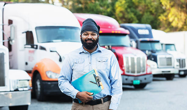 istock Worker with clipboard standing in front of semi-trucks 2233441213