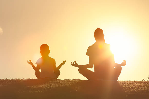 istock Mother and daughter meditating outdoors at sunset. 2233441864