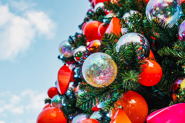 Close-up of a decorated christmas tree with colorful ornaments and a bright blue sky in the background
