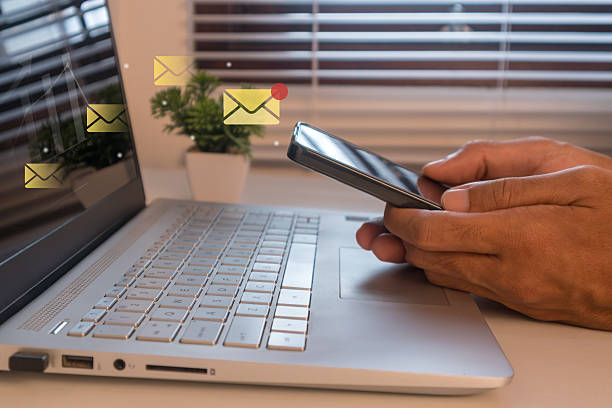 istock A man sending marketing messages or emails using a mobile phone and laptop to engage subscribers and grow business 2233449350