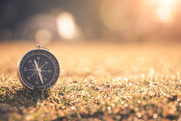 Compass rests on dewy grass, glowing in the warm morning sunlight, guiding the journey ahead.