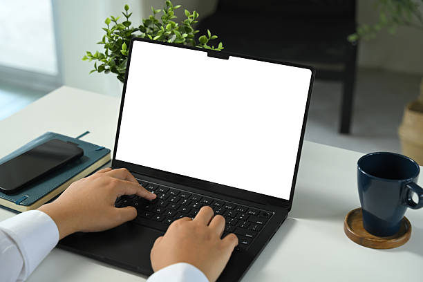 istock Hands typing on laptop with blank screen, at workspace with smartphone and coffee cup 2233455511