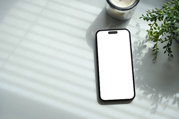 istock Smartphone with blank screen placed on white desk, decorated with plant and candle 2233455519