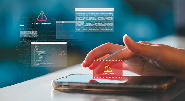 istock Close up of hand using smartphone with digital overlays showing system hacked warning Cybersecurity system hacked warning on smartphone with programming code and digital alert notifications concept 2233459424